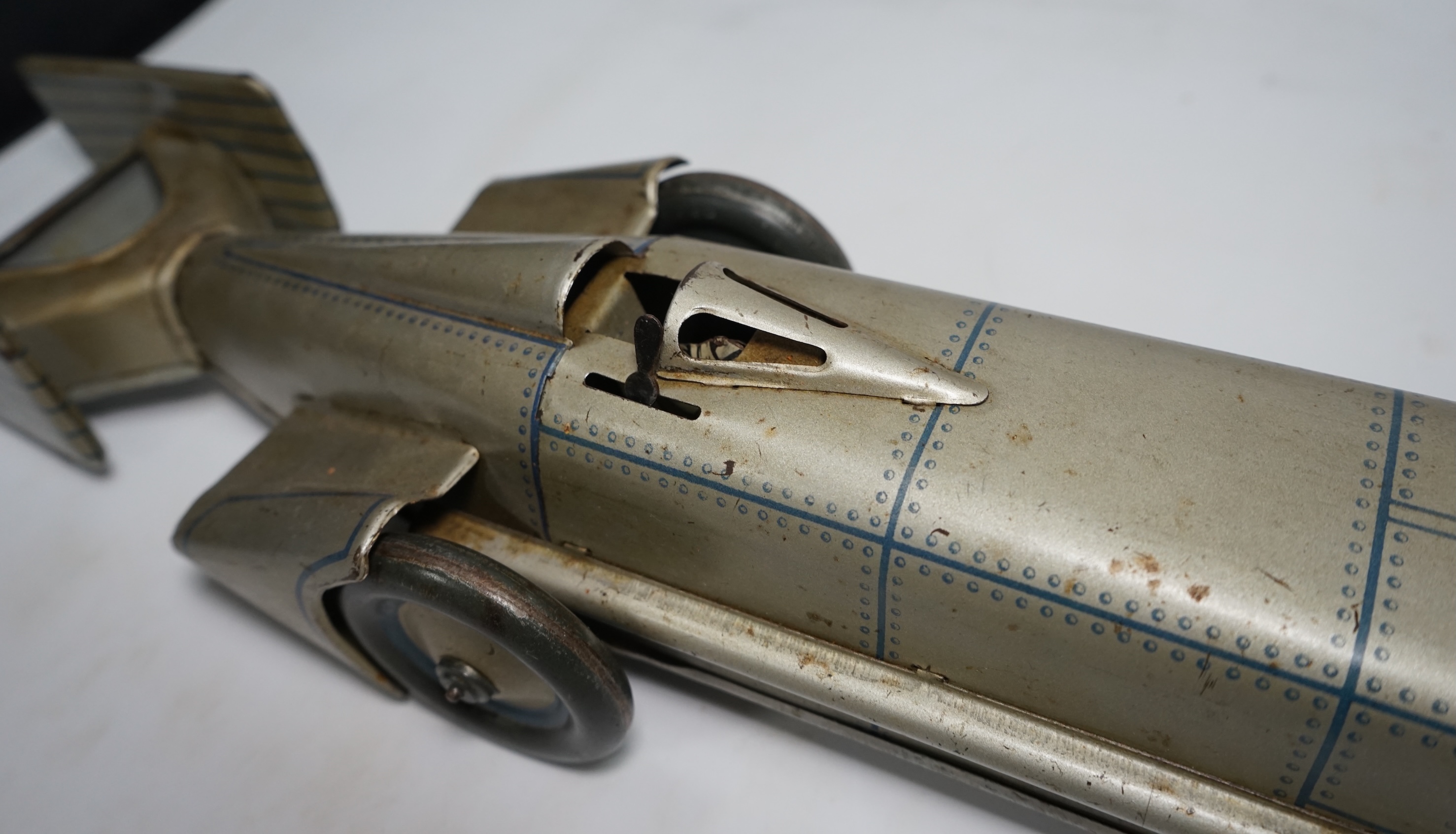 A 1930s Gunthermann (Germany) clockwork tinplate Sunbeam Silver Bullet world record car, with blue printed panel and rivet detail, driver, and Union flags to tail fins, stamped with ‘Foreign’ to underside, 56cm long. Con